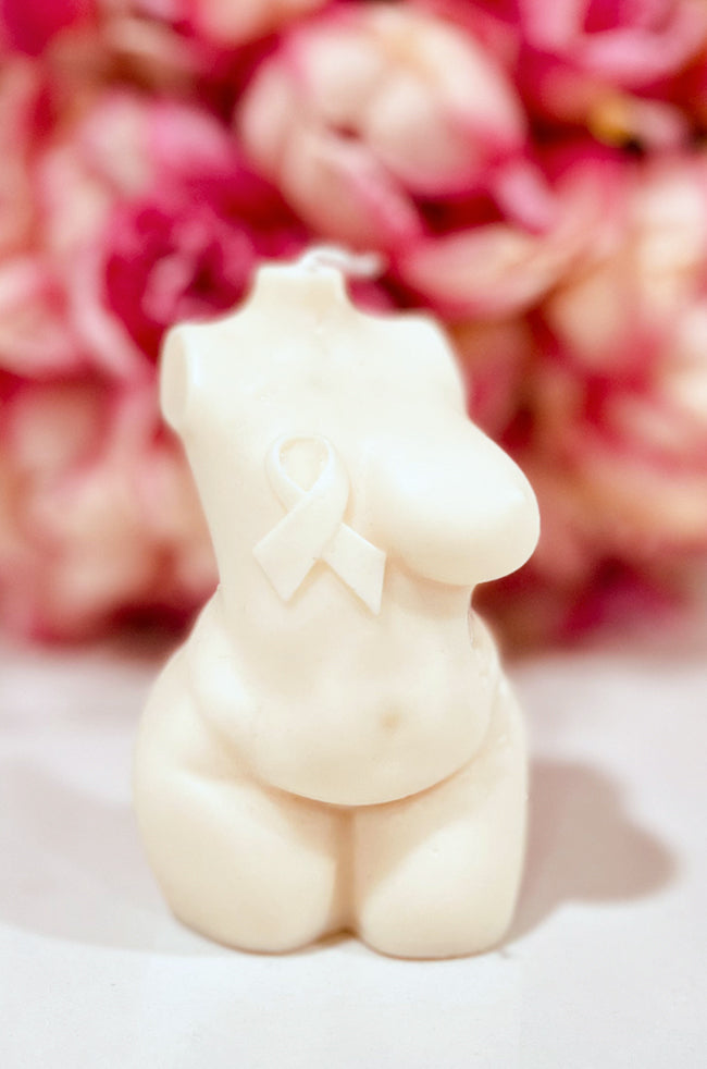 Resilient Warrior Candle: A body candle featuring an awareness ribbon, displayed against pink flowers.