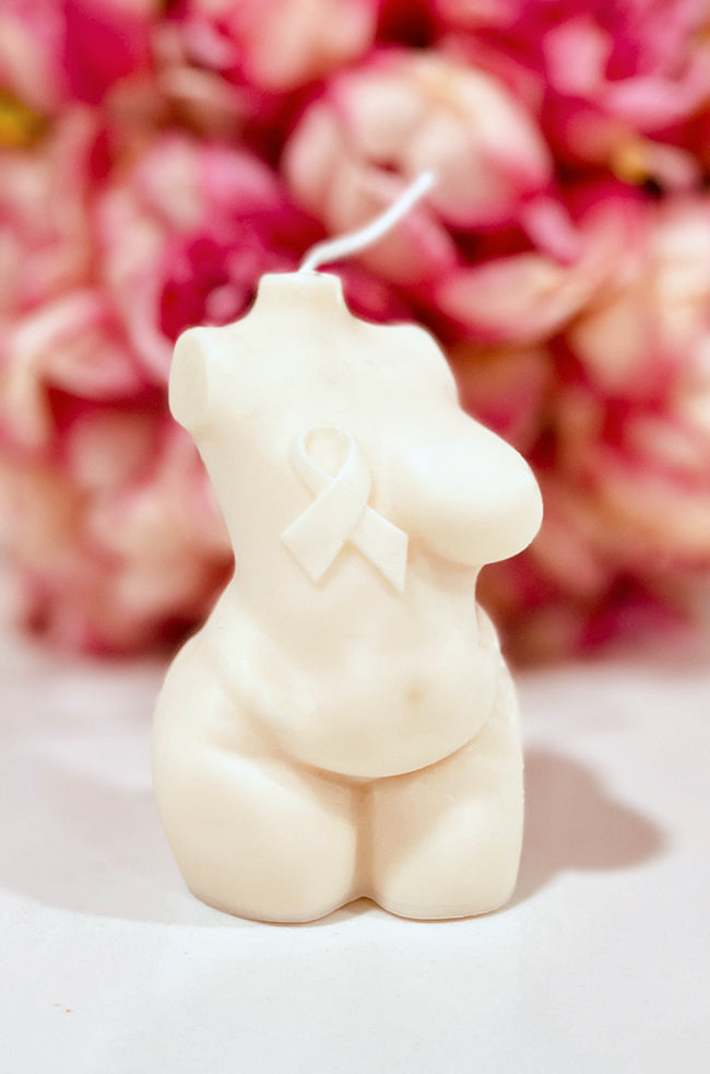 Resilient Warrior Candle: Front view of the ivory Resilient Warrior sculptural candle with awareness ribbon and pink floral background.