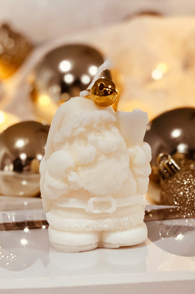Santa's Light Candle: Ivory Santa’s sculptural Christmas candle with a gold bell on top, styled with festive silver and gold holiday ornaments.