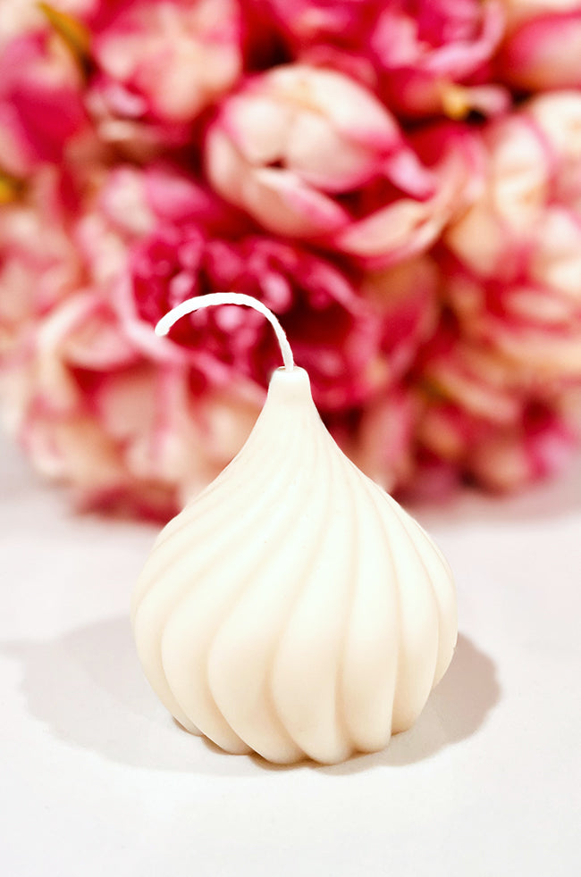Teardrop Candle: Ivory Teardrop Candle by Dahil Bar with smooth sculpted ridges, displayed against a pink floral background for a soft, luxurious aesthetic.