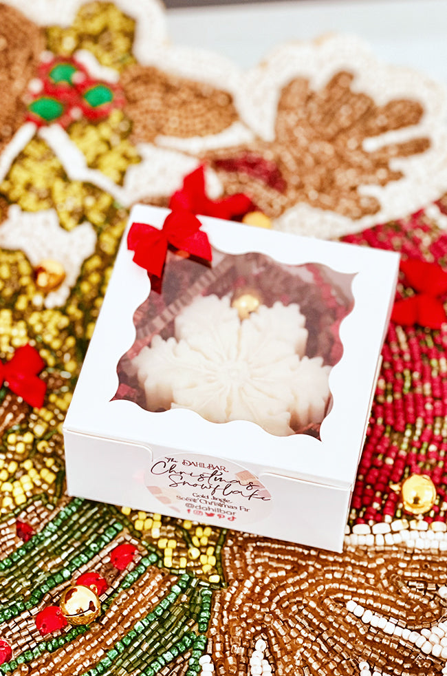The Christmas Snowflake Candle: Boxed Christmas Snowflake candle with red bow, clear window, and Dahil Bar holiday gift label.