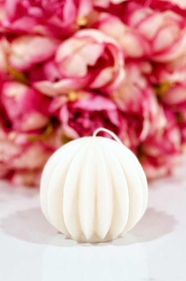 The Oval Light Candle: Minimalist handmade oval candle with grooved round design, The Oval Light, styled with pink floral background for luxury home décor.