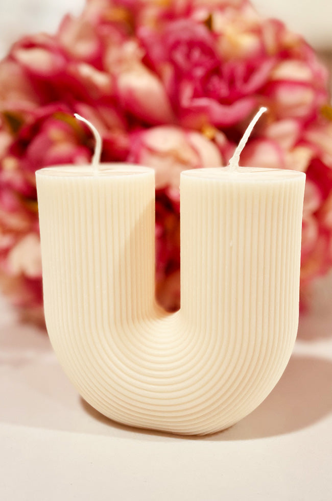Twin Candle: Handmade U-shaped Twin Candle with two wicks and ribbed texture, displayed in front of pink flowers — a sculptural minimalist candle for luxury home décor.
